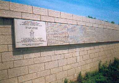 Die kreisrunde Mauer mit den Namenstafeln, die den deutschen Gefallenenfriedhof umgiebt,von außen gesehen.